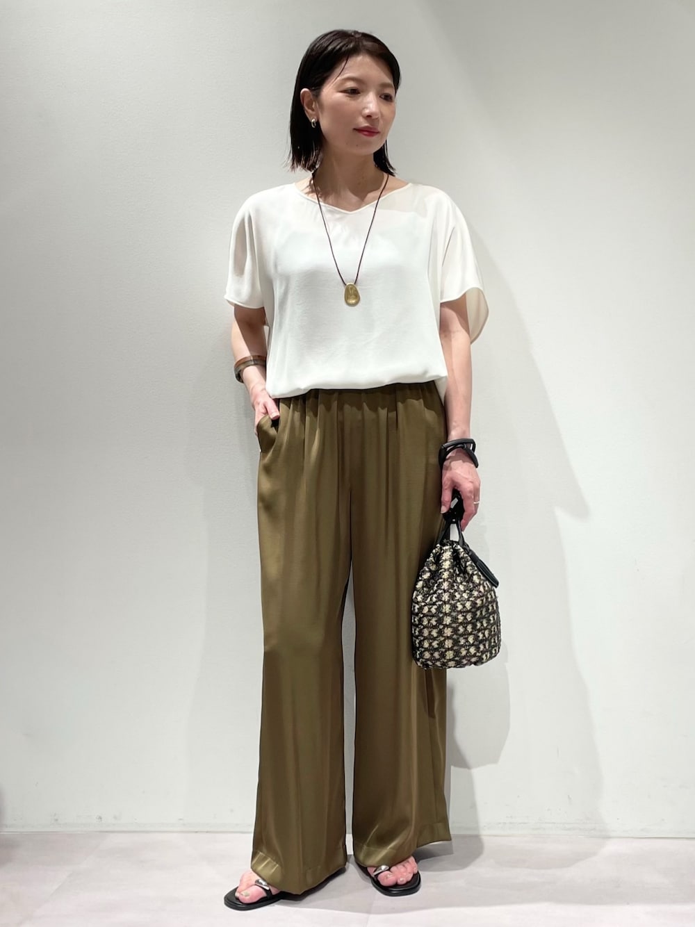 ホワイト系のシャツ/ブラウス、ブラック系のショルダーバッグ、グリーン系のその他パンツを着用したレディースの春コーディネートの1枚目の写真