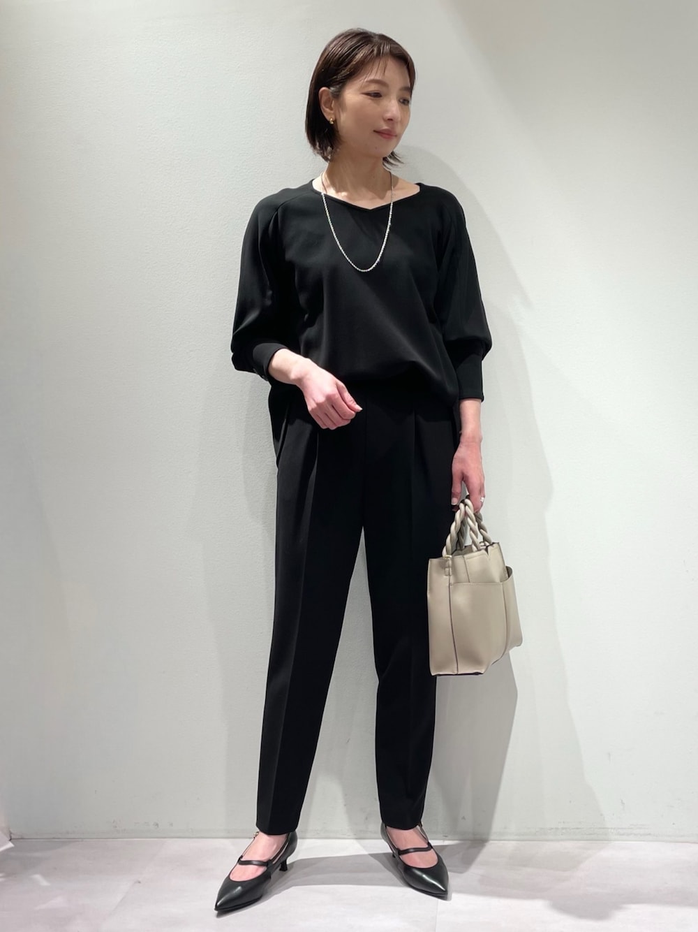 ブラック系のシャツ/ブラウス、ブラック系のスラックス、ブラック系のパンプスを着用したレディースの冬コーディネートの1枚目の写真