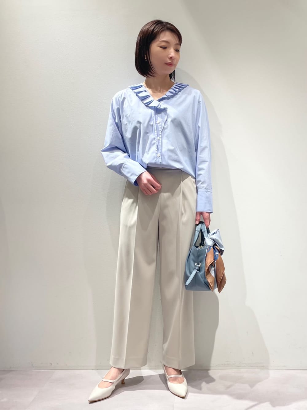 ブルー系のシャツ/ブラウス、ベージュ系のスラックス、ブルー系のショルダーバッグを着用したレディースの冬コーディネートの1枚目の写真