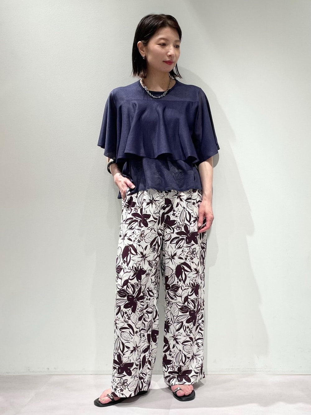 レッド系のその他パンツ、ブルー系のニット/セーター、シルバー系のネックレスを着用したレディースの春コーディネートの1枚目の写真