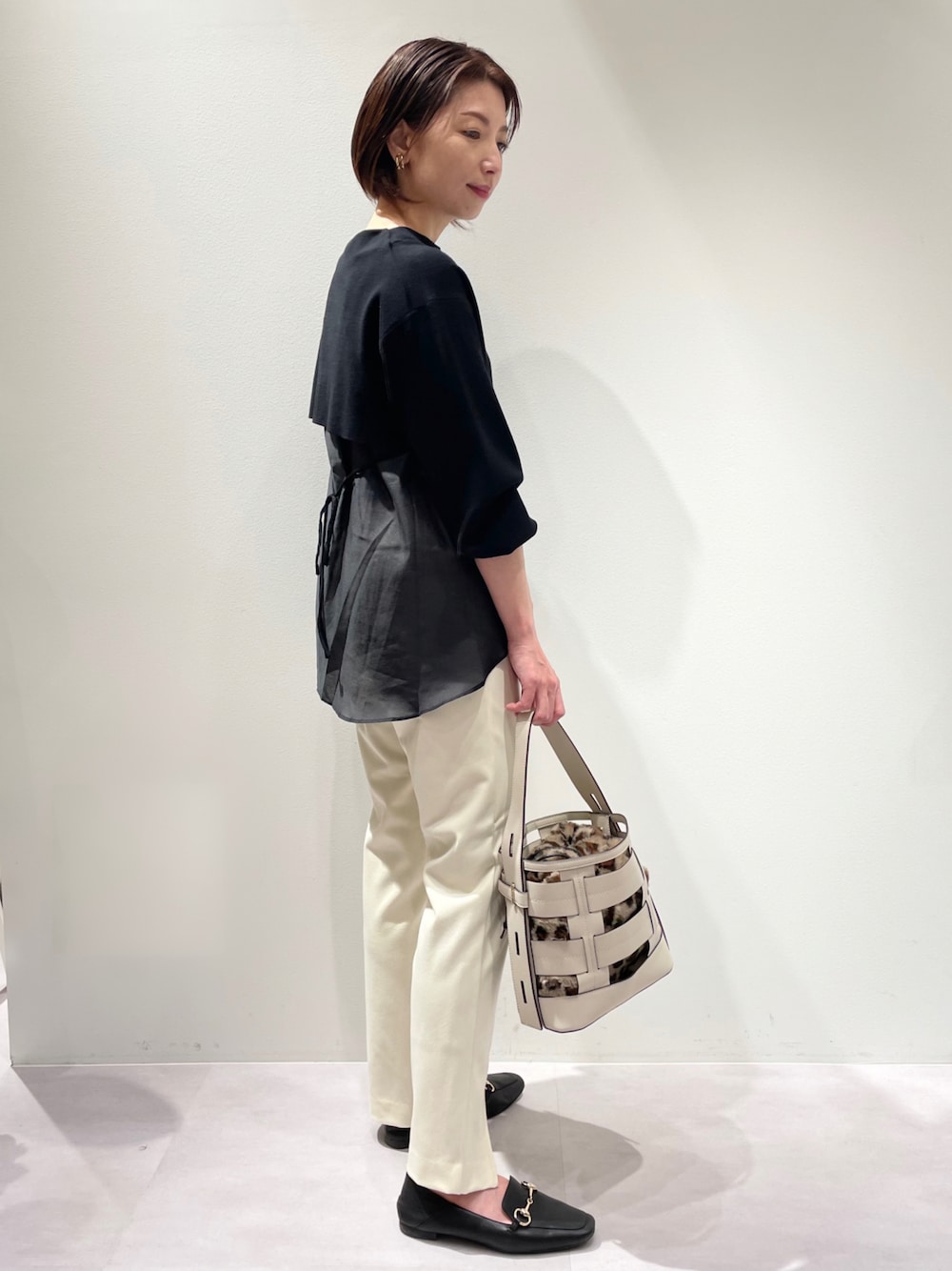 ブラック系のニット/セーター、ベージュ系のハンドバッグ、ブラック系のローファーを着用したレディースの秋コーディネートの1枚目の写真