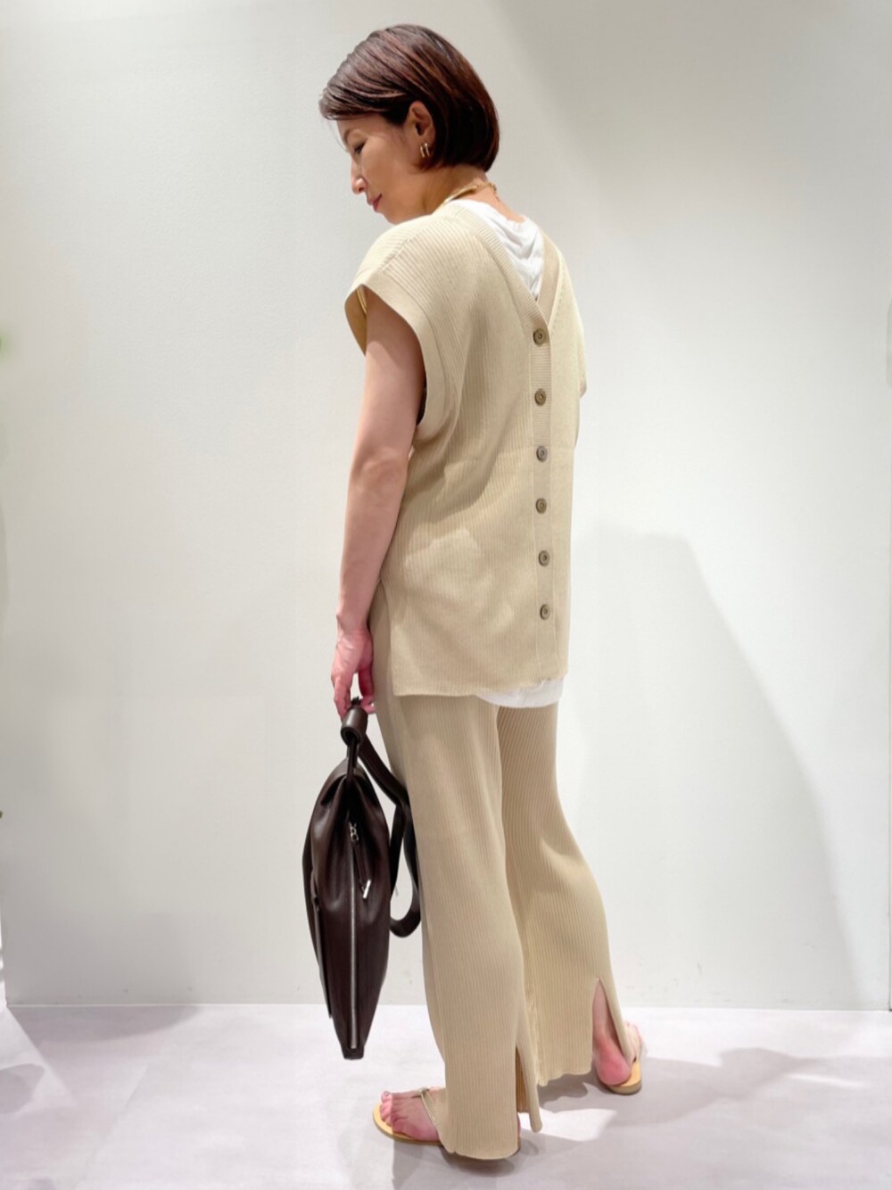 ベージュ系のニット/セーター、ホワイト系のTシャツ/カットソー、ベージュ系のその他パンツを着用したレディースの夏コーディネートの1枚目の写真