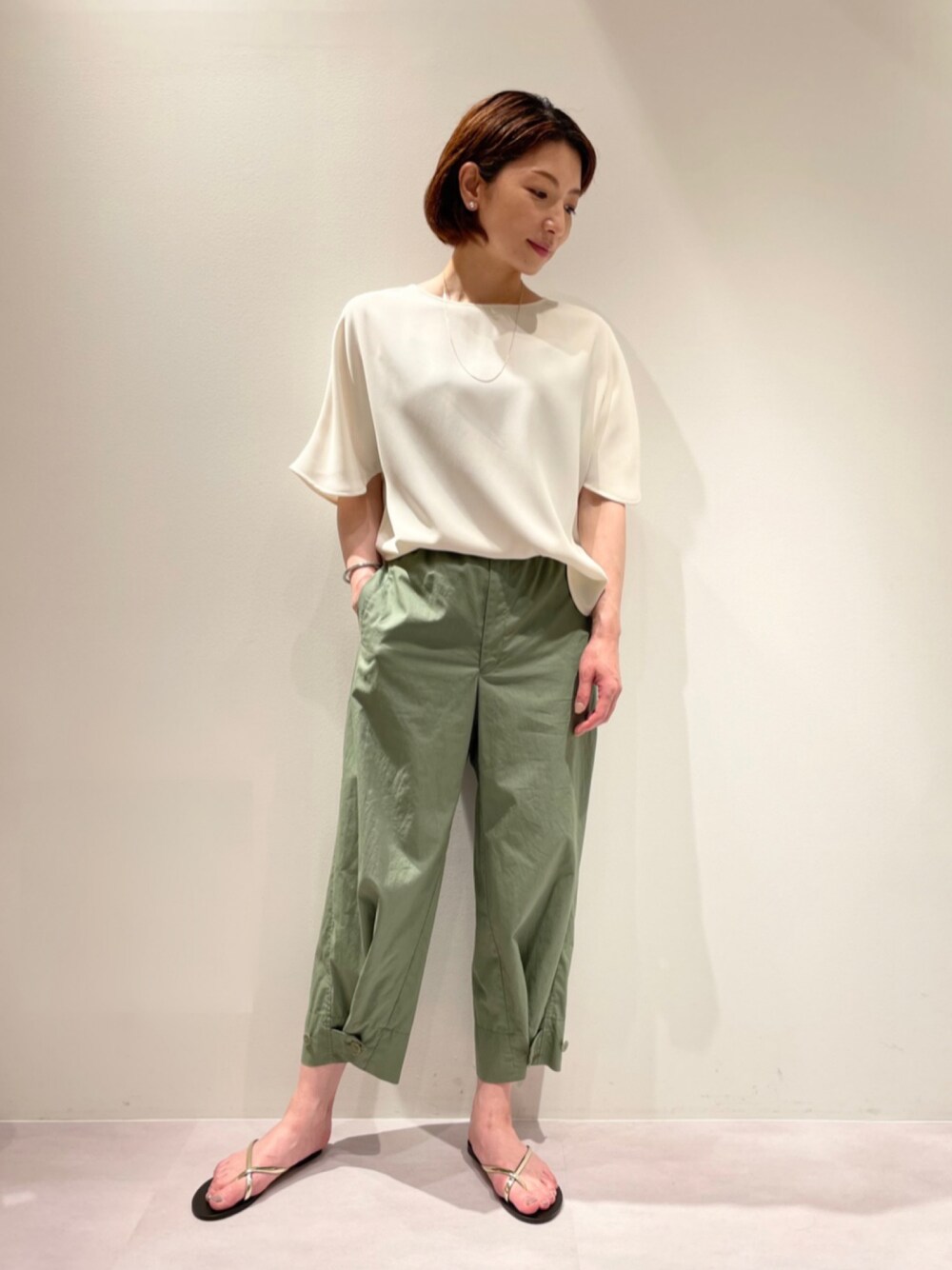グリーン系のカーゴパンツ、ベージュ系のシャツ/ブラウス、ゴールド系のネックレスを着用したレディースの春コーディネートの1枚目の写真