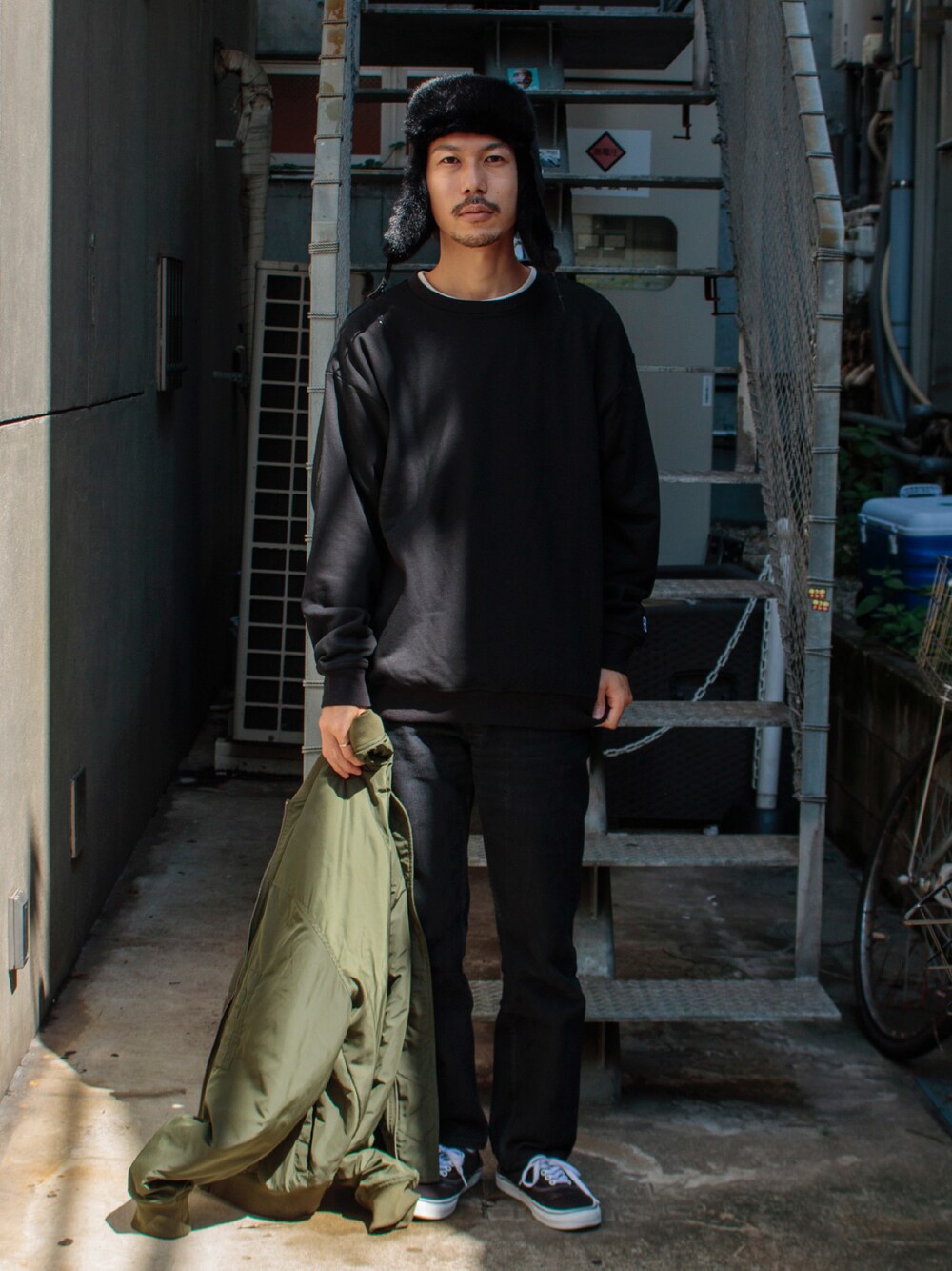 ブラック系のスウェット、グリーン系のブルゾン、ブラック系のスニーカーを着用したメンズの秋コーディネートの1枚目の写真