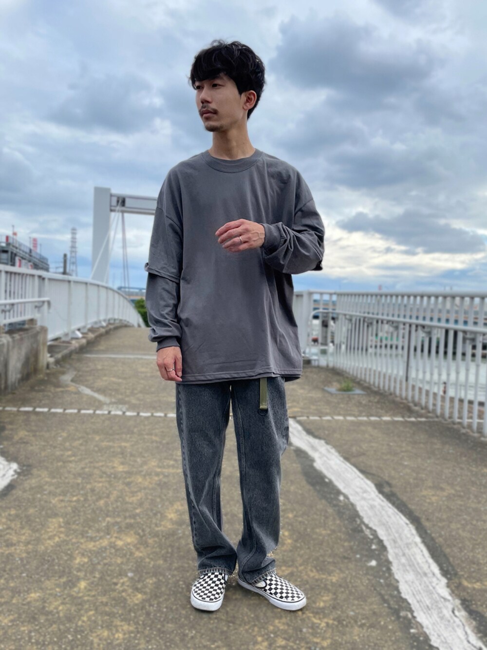 ホワイト系のスリッポン、グレー系のTシャツ/カットソー、ブラック系のデニムパンツを着用したメンズの夏コーディネートの1枚目の写真