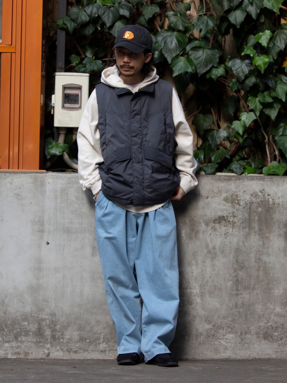 グレー系のベスト、ベージュ系のパーカー、ブルー系のその他パンツを着用したメンズの春コーディネートの1枚目の写真