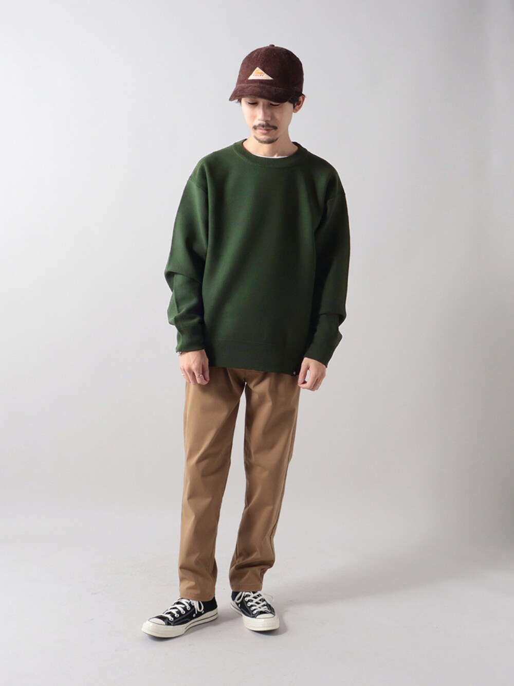 グリーン系のニット/セーター、ベージュ系のその他パンツ、ブラック系のスニーカーを着用したメンズの秋コーディネートの1枚目の写真