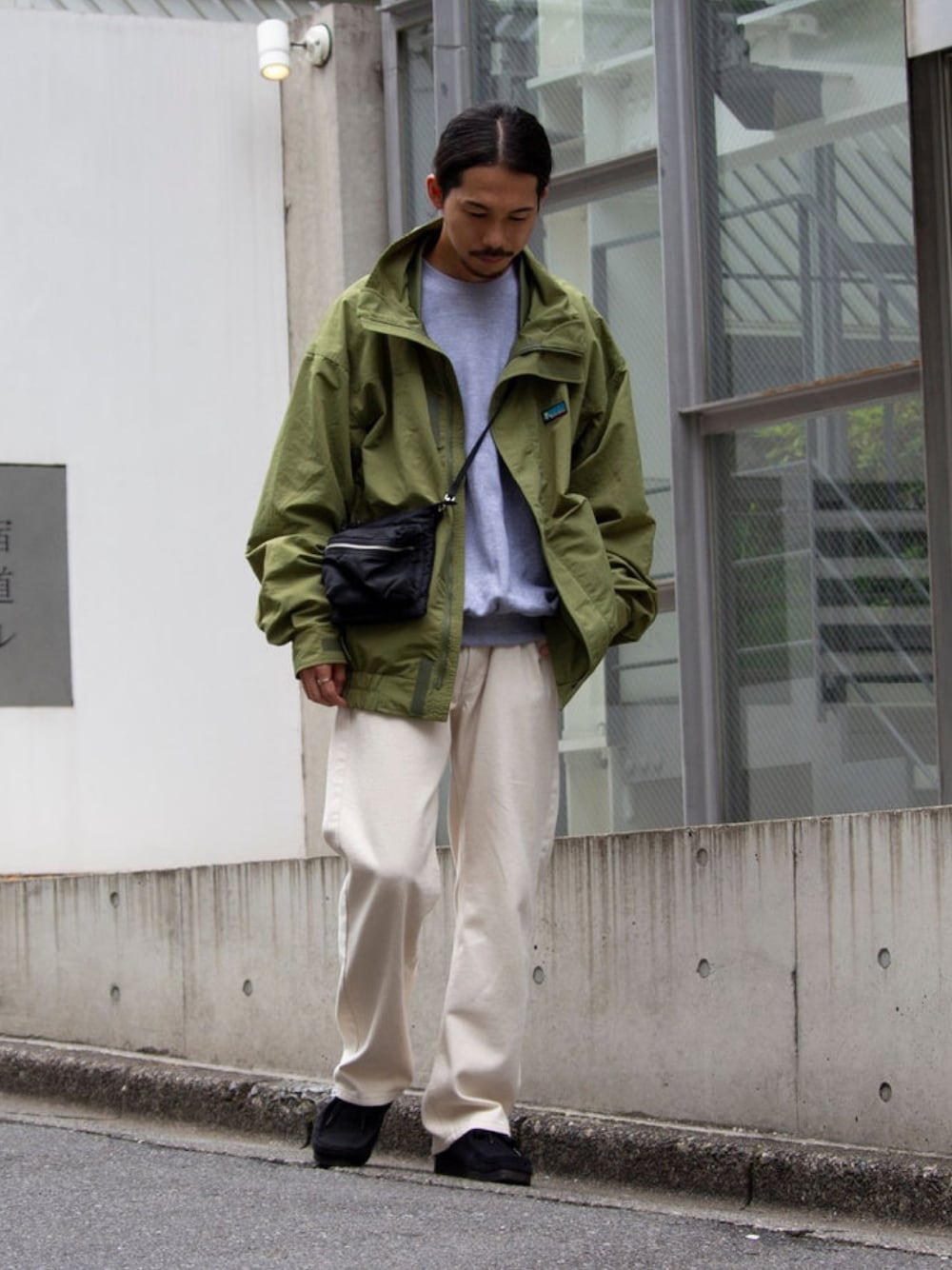 グリーン系のナイロンジャケット、グレー系のスウェット、ホワイト系のデニムパンツを着用したメンズの夏コーディネートの1枚目の写真