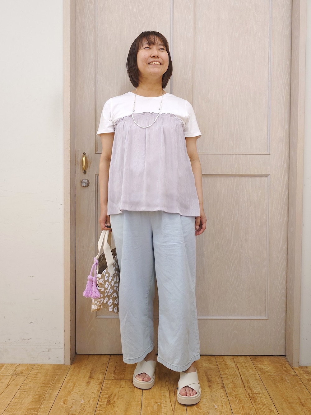 グレー系のTシャツ/カットソー、ブルー系のデニムパンツ、ベージュ系のサンダルを着用したレディースの夏コーディネートの1枚目の写真