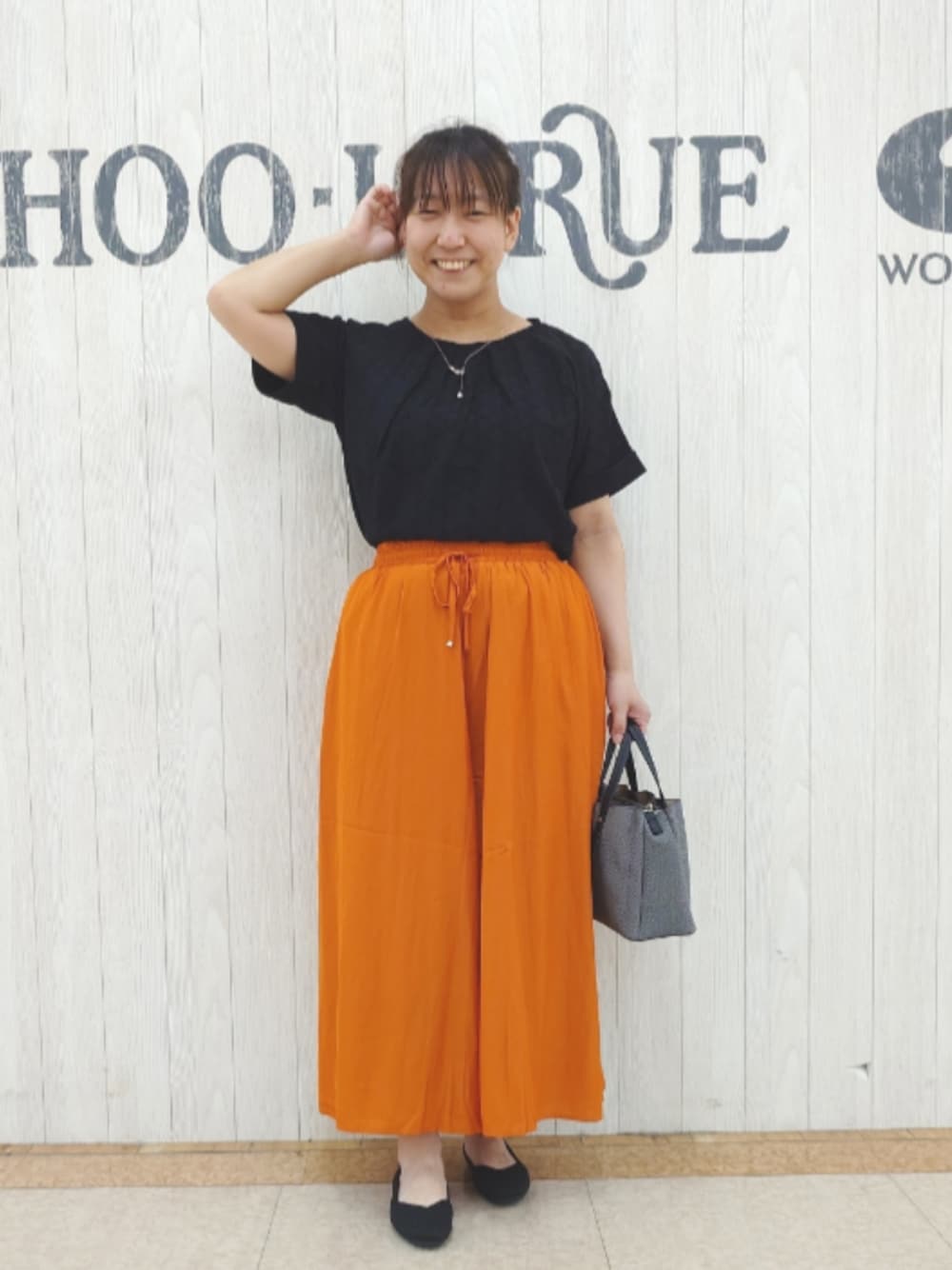 ブラック系のTシャツ/カットソー、オレンジ系のその他パンツ、ブラック系のトートバッグを着用したレディースの秋コーディネートの1枚目の写真