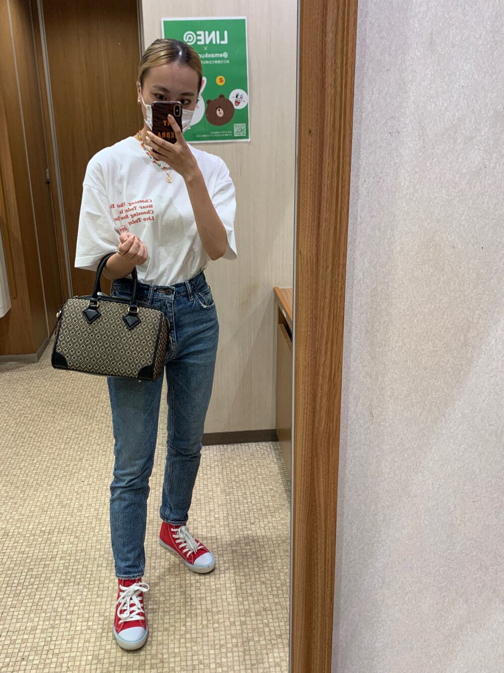 ホワイト系のTシャツ/カットソー、ブラウン系のボストンバッグ、ブルー系のデニムパンツを着用したレディースの秋コーディネートの1枚目の写真