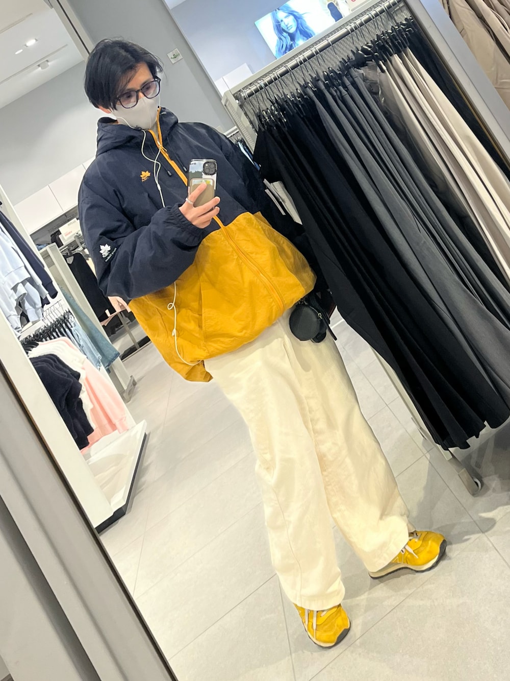 イエロー系のスニーカー、ホワイト系のパンツ、ブルー系のナイロンジャケットを着用したメンズの冬コーディネートの1枚目の写真