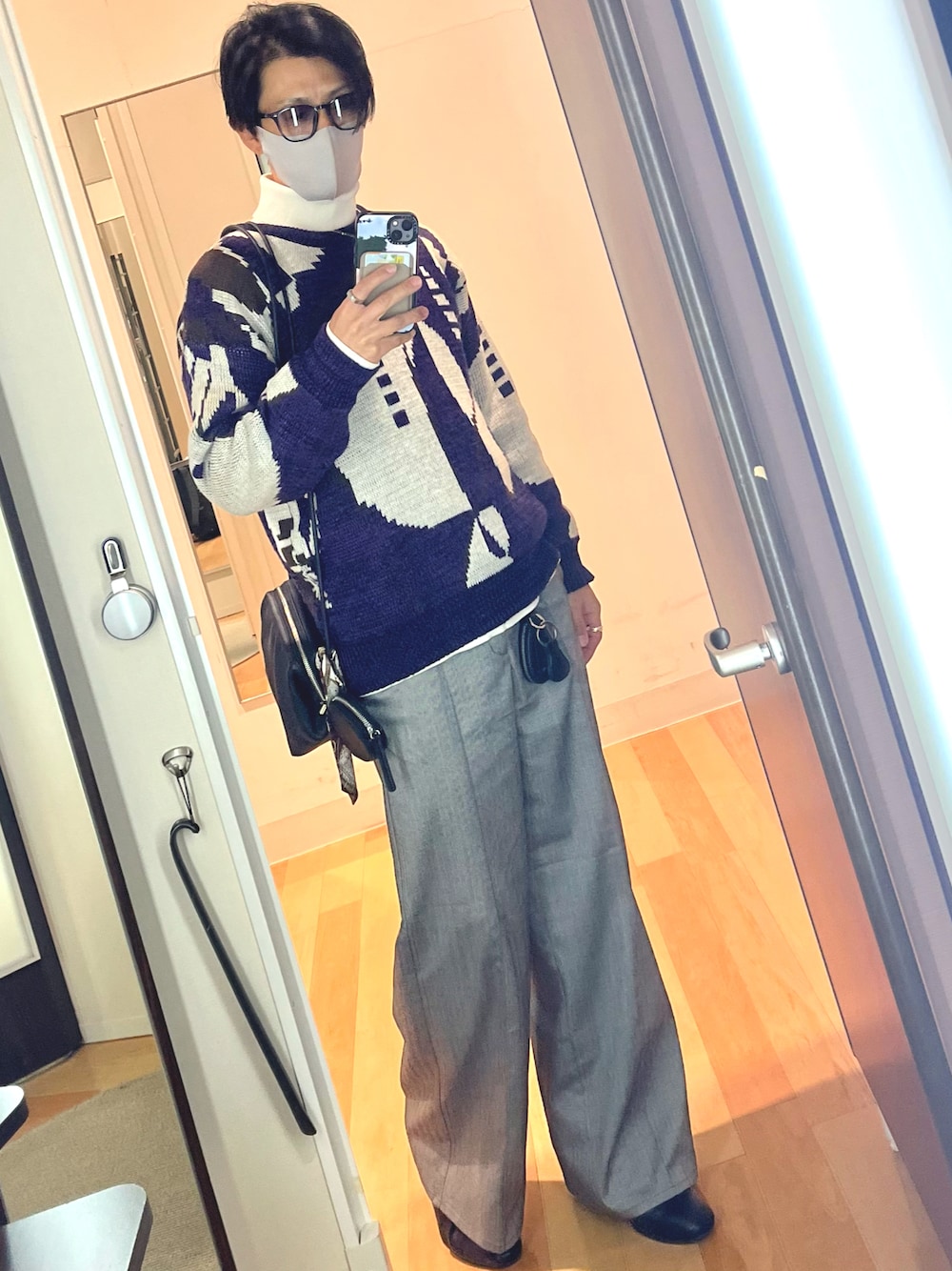 グレー系のスラックス、ブラック系のショルダーバッグ、パープル系のニット/セーターを着用したメンズの冬コーディネートの1枚目の写真