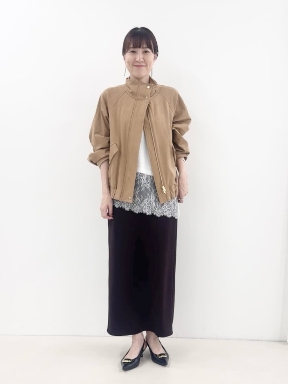 ブラウン系のスカート、ブラック系のパンプス、イエロー系のブルゾンを着用したレディースの秋コーディネートの1枚目の写真