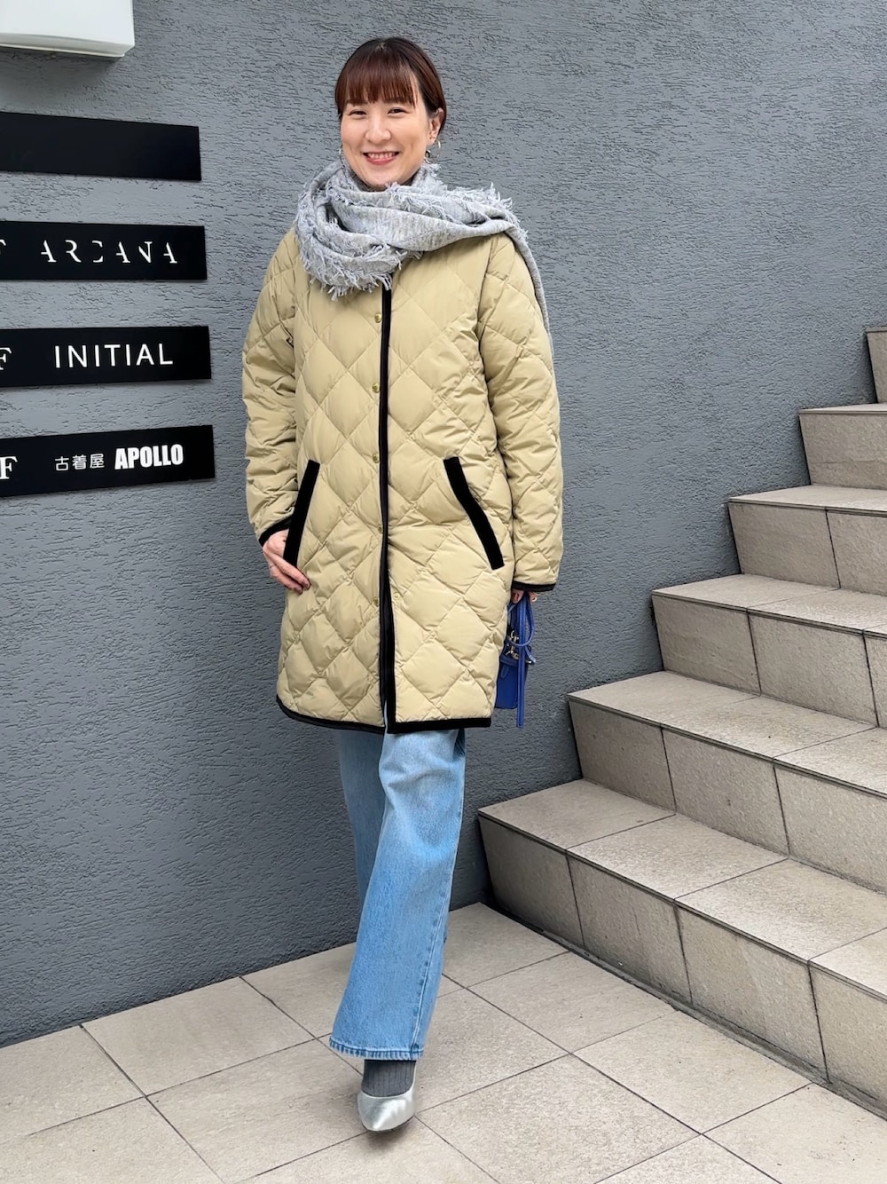 ブルー系のデニムパンツ、ブルー系のショルダーバッグ、ベージュ系のダウンジャケット/コートを着用したレディースの秋コーディネートの1枚目の写真