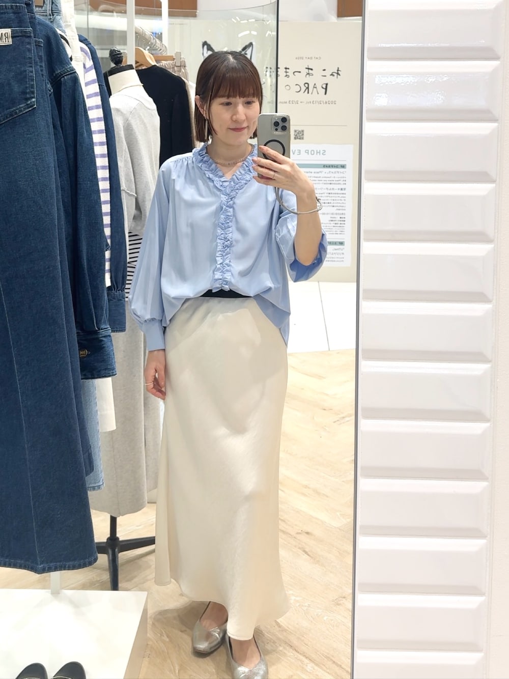 ブルー系のシャツ/ブラウス、ホワイト系のスカート、グレー系のネックレスを着用したレディースの春コーディネートの1枚目の写真