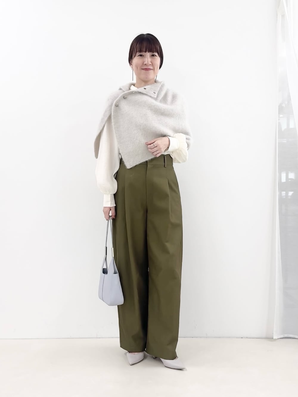 ブルー系のショルダーバッグ、グリーン系のチノパンツ、ホワイト系のシャツ/ブラウスを着用したレディースの秋コーディネートの1枚目の写真