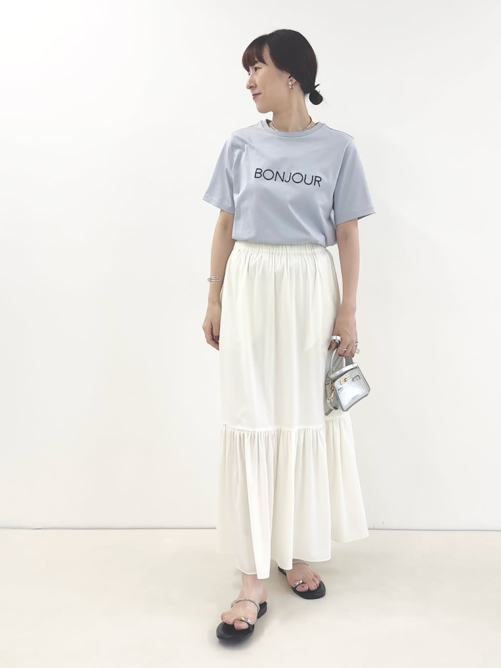 ホワイト系のスカート、シルバー系のサンダル、ブルー系のTシャツ/カットソーを着用したレディースの夏コーディネートの1枚目の写真