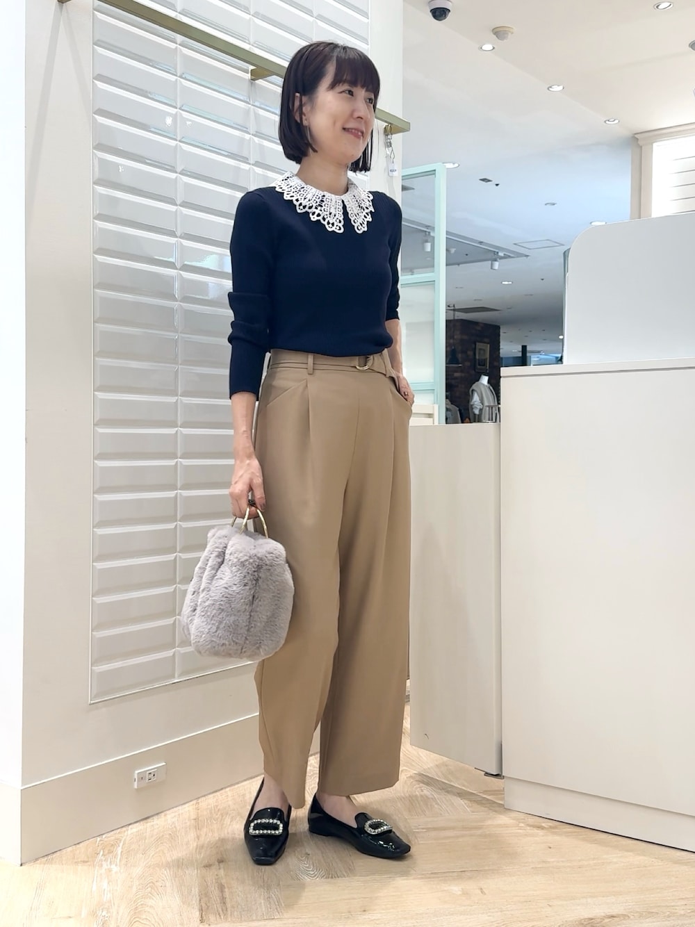 ベージュ系のその他パンツ、グレー系のショルダーバッグ、ブルー系のニット/セーターを着用したレディースの秋コーディネートの1枚目の写真