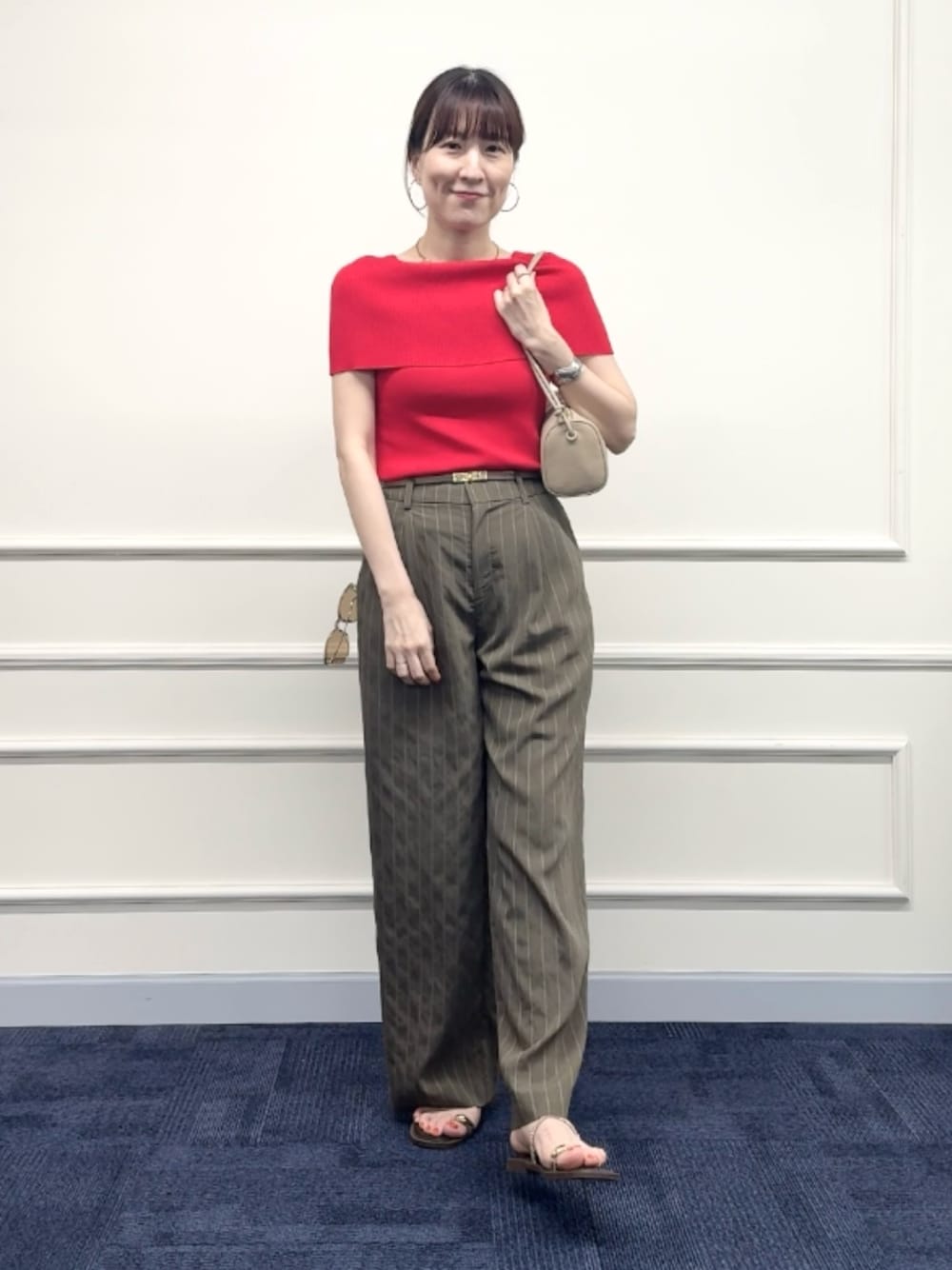 レッド系のニット/セーター、グリーン系のその他パンツ、ベージュ系のショルダーバッグを着用したレディースの夏コーディネートの1枚目の写真