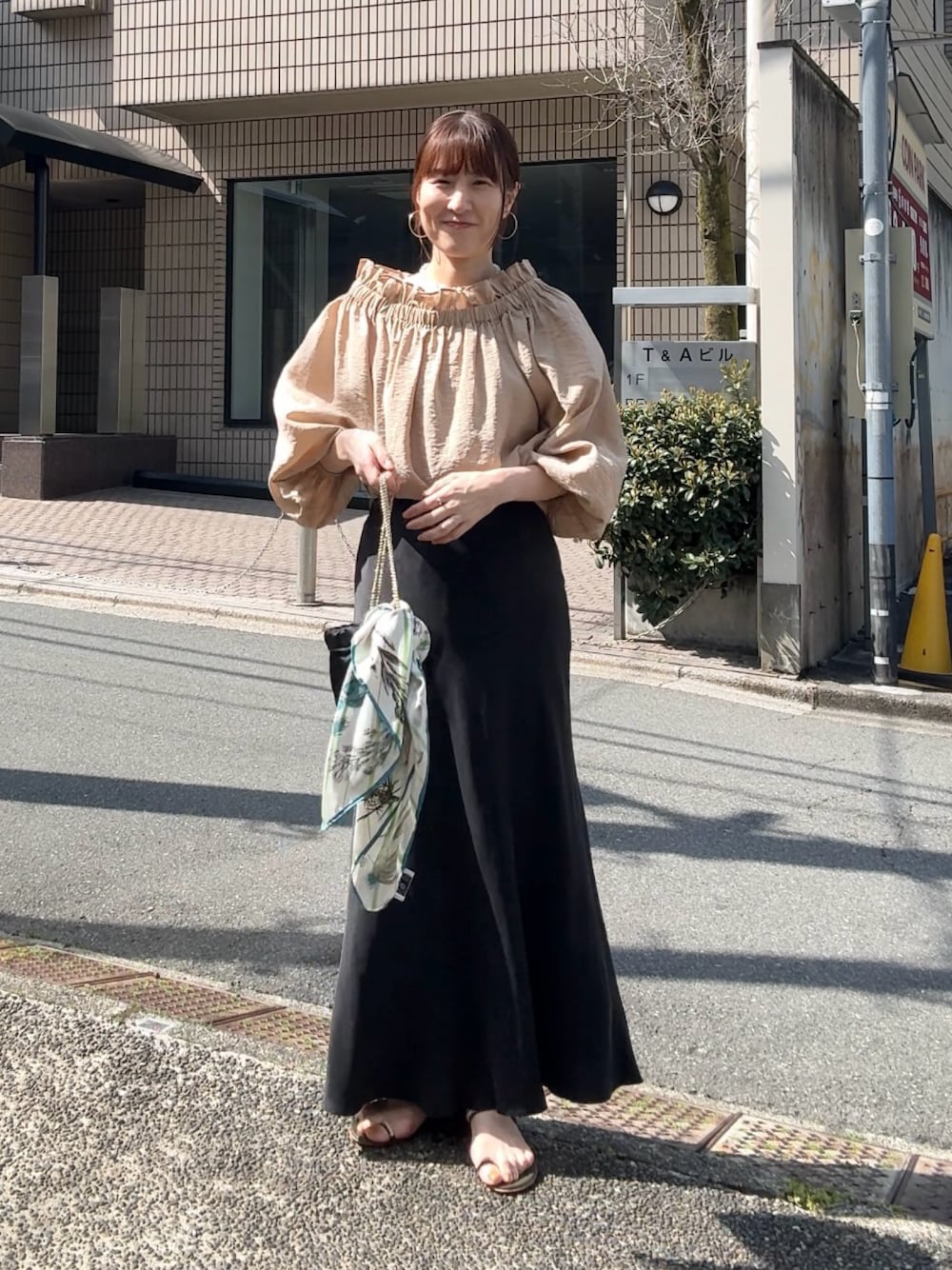 ブラック系のスカート、イエロー系のシャツ/ブラウス、その他のネックレスを着用したレディースの春コーディネートの1枚目の写真