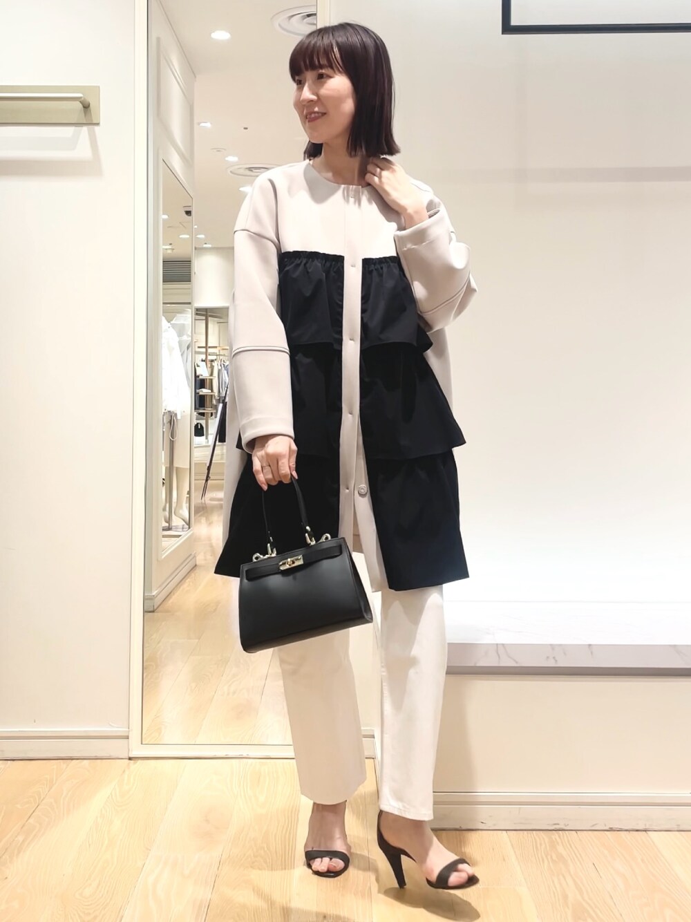 ベージュ系のその他アウター、ブラック系のショルダーバッグを着用したレディースの春コーディネートの1枚目の写真