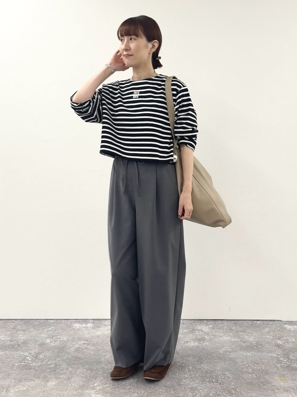 ブラック系のTシャツ/カットソー、ベージュ系のショルダーバッグ、グレー系のその他パンツを着用したレディースの秋コーディネートの1枚目の写真