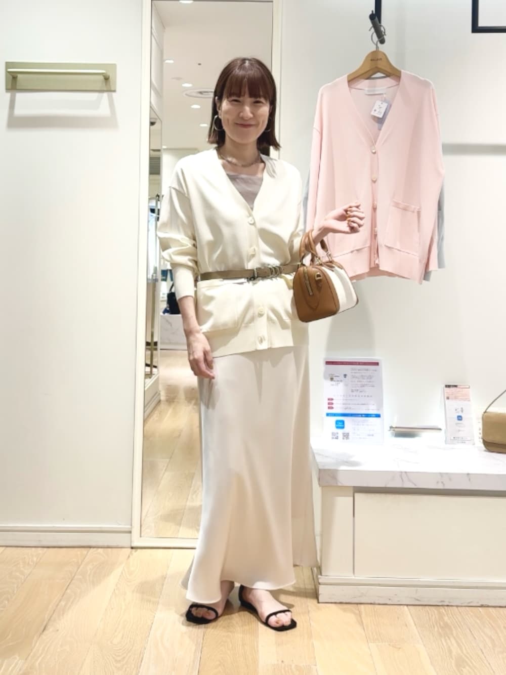 ベージュ系のタンクトップ、ホワイト系のスカート、ブラウン系のボストンバッグを着用したレディースの春コーディネートの1枚目の写真