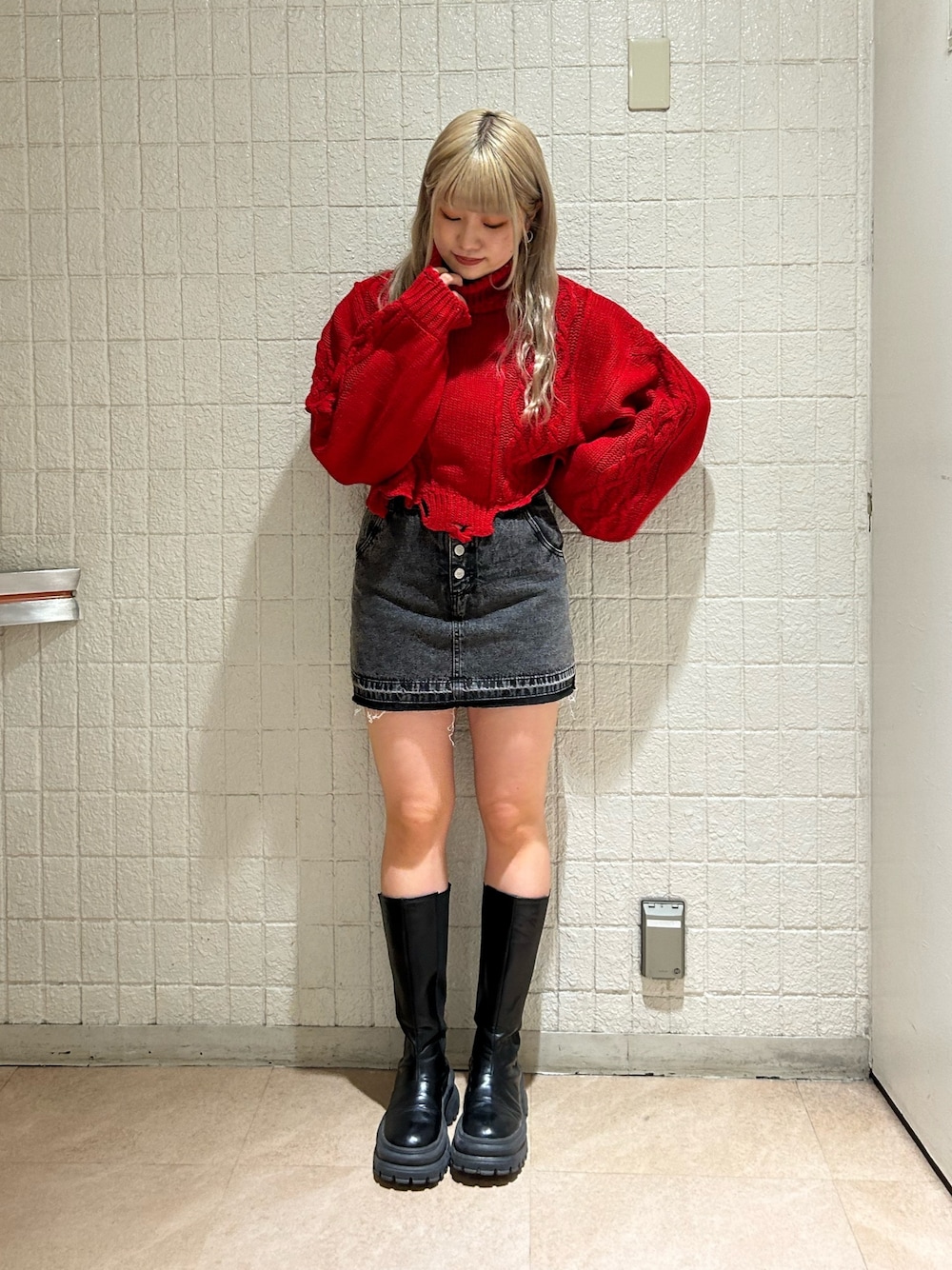 レッド系のニット/セーター、ブラック系のデニムパンツ、ブラック系のブーツを着用したレディースの冬コーディネートの1枚目の写真