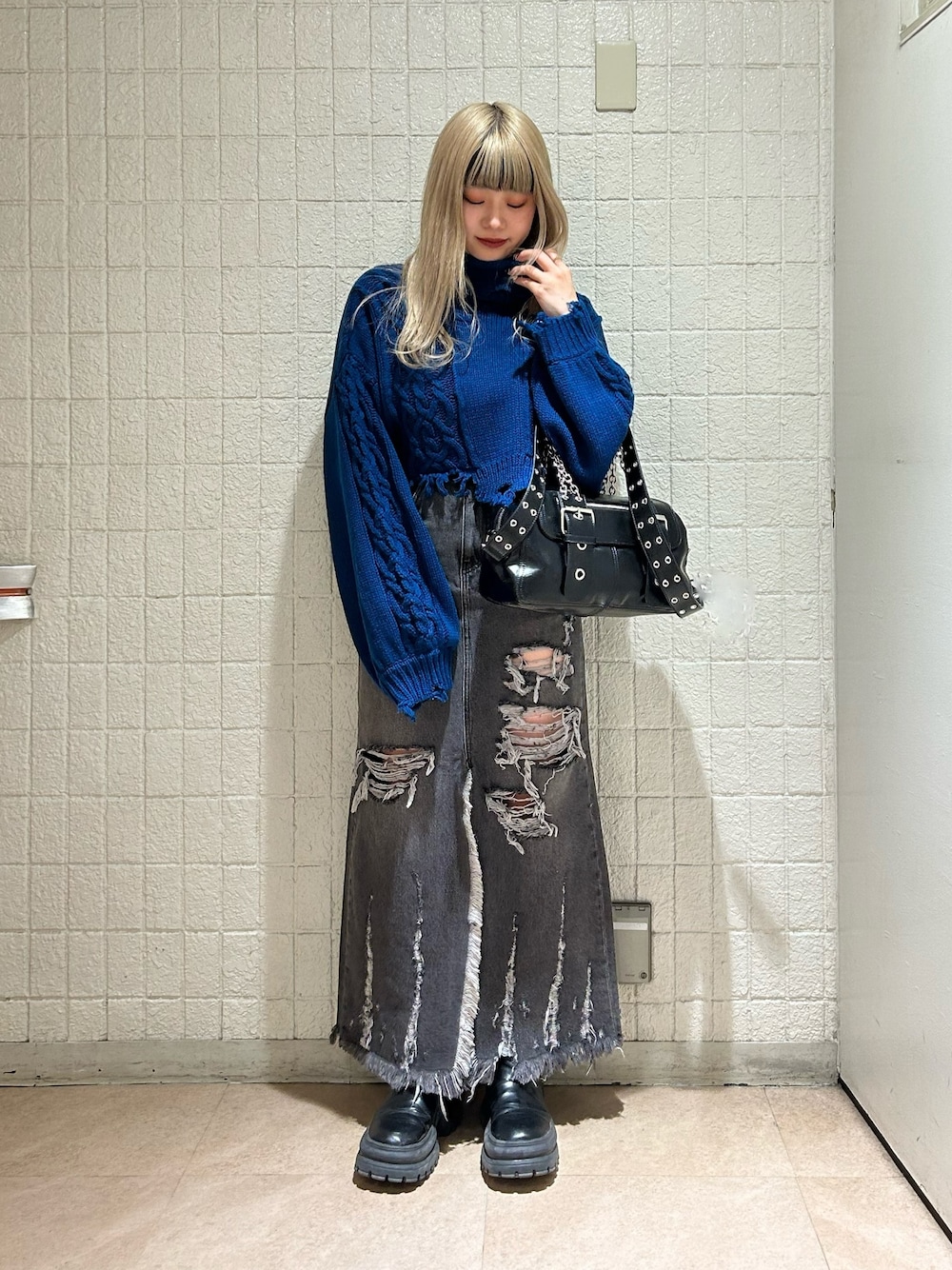 ブラック系のデニムスカート、ブルー系のニット/セーター、ブラック系のブーツを着用したレディースの冬コーディネートの1枚目の写真