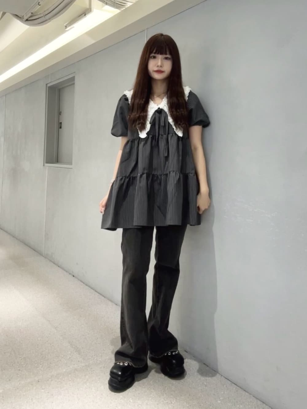 グレー系のワンピース、ブラック系のデニムパンツ、ブラック系のパンプスを着用したレディースの夏コーディネートの1枚目の写真