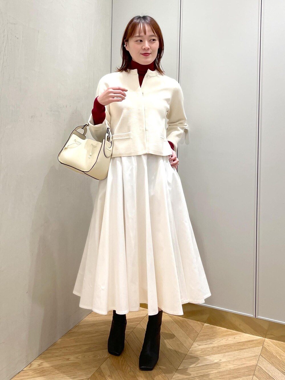 ブラック系のブーツ、ホワイト系のスカート、ホワイト系のノーカラージャケットを着用したレディースの冬コーディネートの1枚目の写真