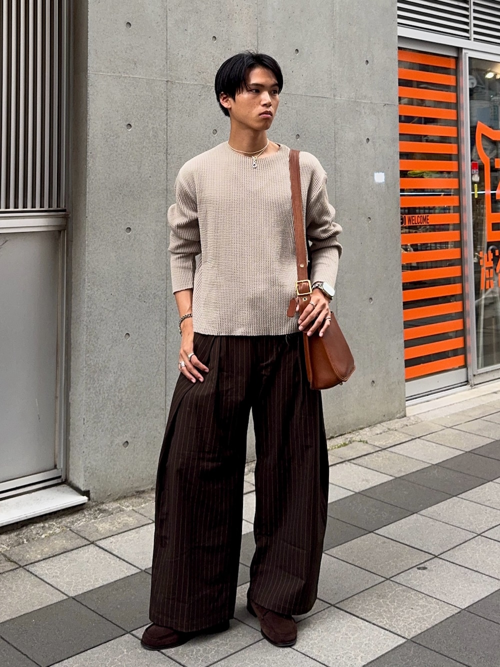 グリーン系のTシャツ/カットソー、ブラウン系のスラックス、ブラウン系のショルダーバッグを着用したメンズの夏コーディネートの1枚目の写真