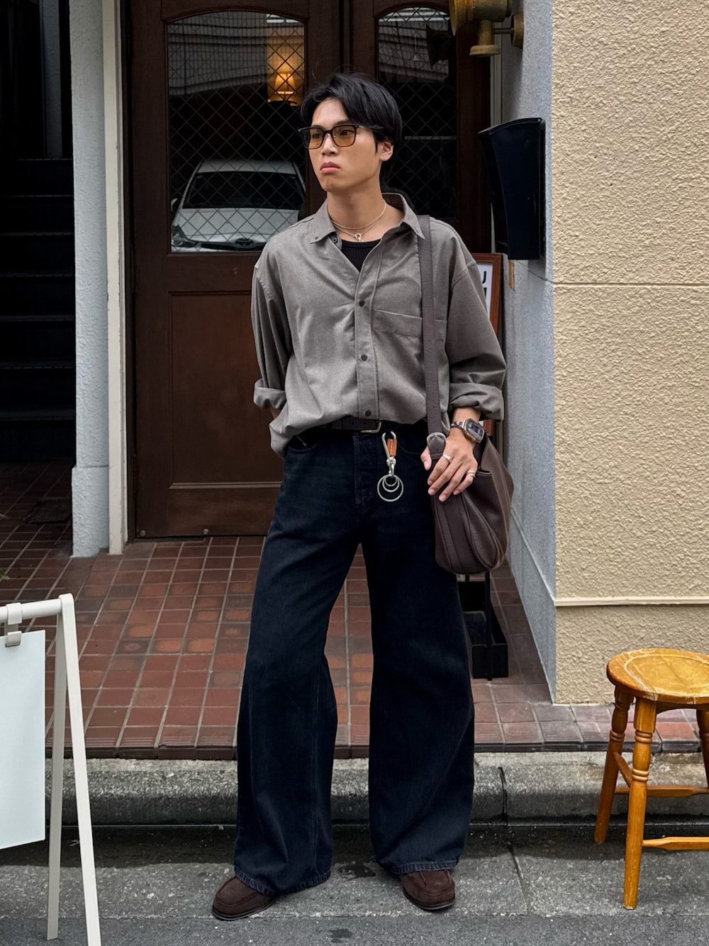ブラック系のタンクトップ、ブラック系のデニムパンツ、ブラウン系のショルダーバッグを着用したメンズの秋コーディネートの1枚目の写真