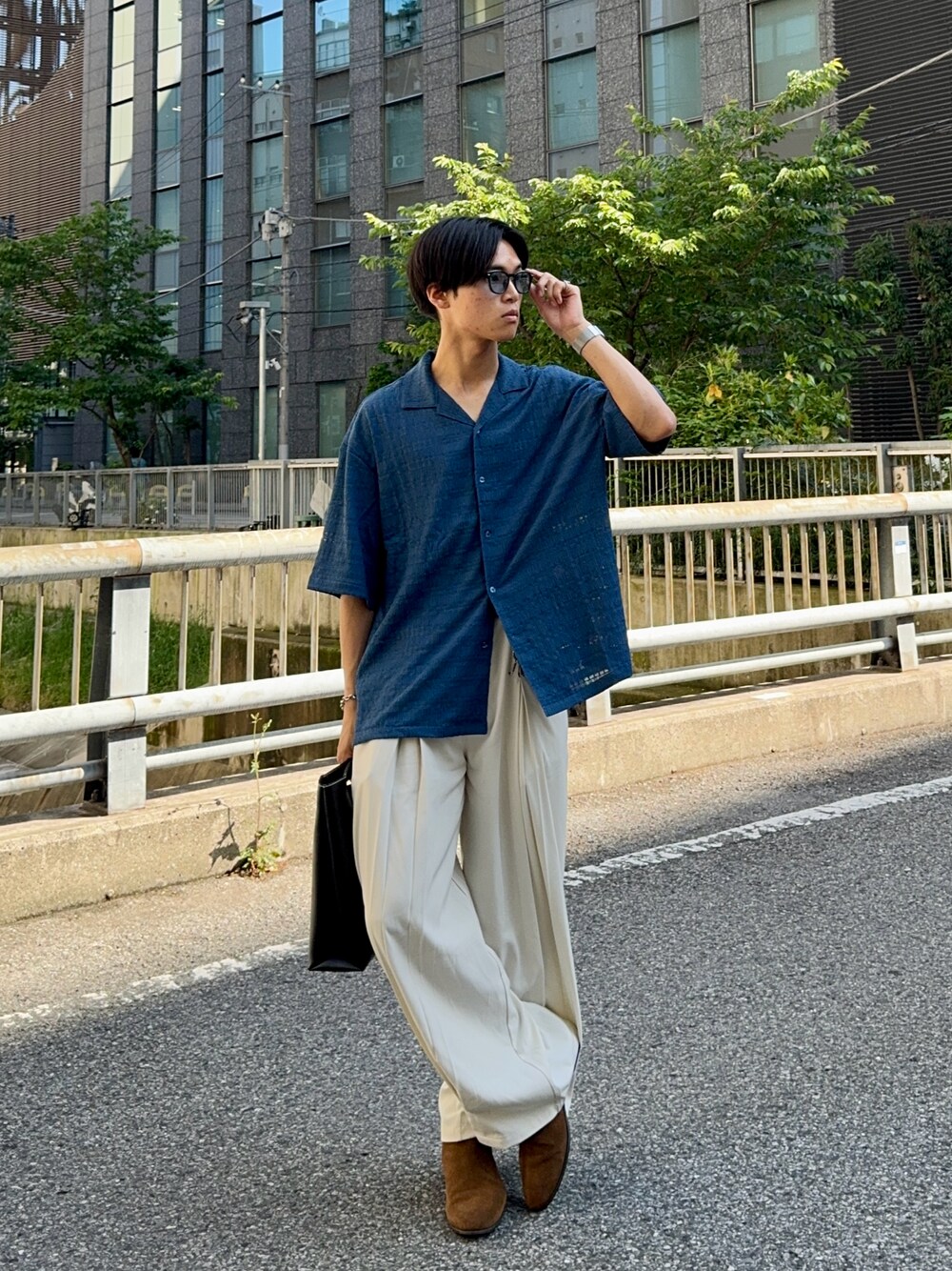 ブルー系のシャツ/ブラウス、ホワイト系のスラックス、ブラック系のハンドバッグを着用したメンズの春コーディネートの1枚目の写真