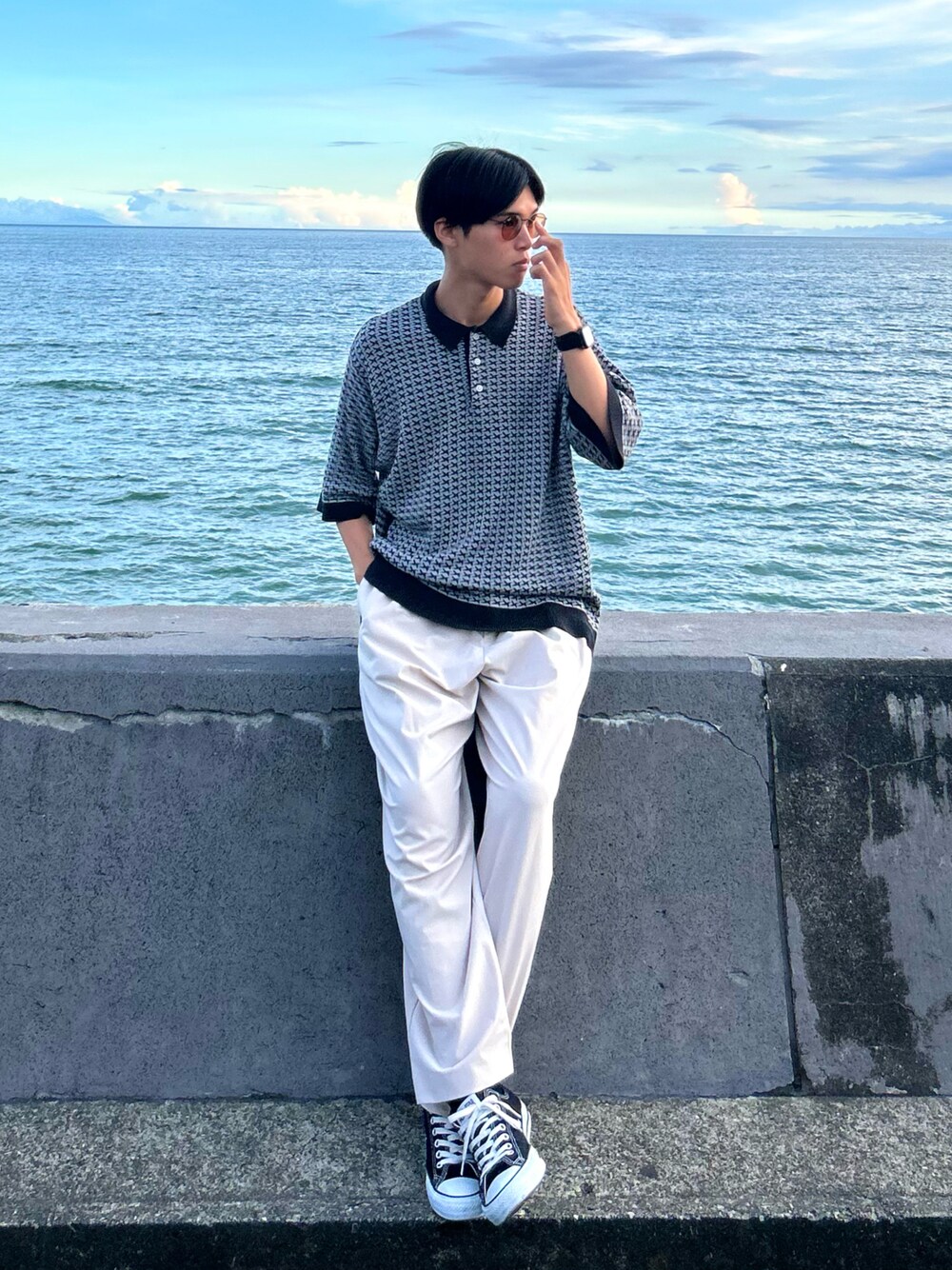 ブラック系のスニーカー、ベージュ系のパンツ、グレー系のポロシャツを着用したメンズの夏コーディネートの1枚目の写真