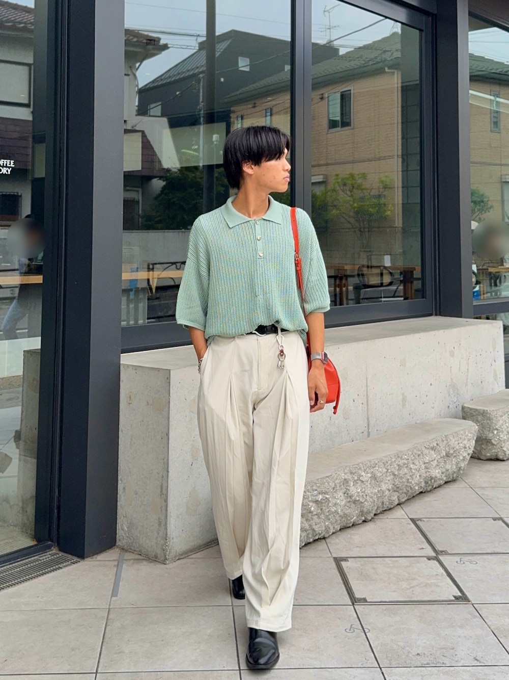 グリーン系のポロシャツ、オレンジ系のバッグ、ホワイト系のスラックスを着用したメンズの夏コーディネートの1枚目の写真