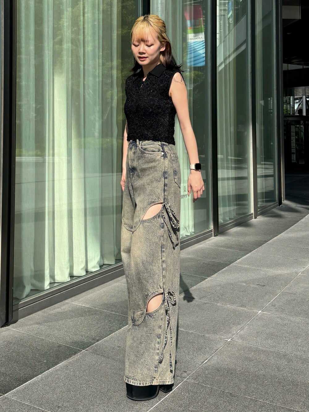 ブラック系のニット/セーター、ブルー系のデニムパンツ、ブラック系のサンダルを着用したレディースの夏コーディネートの1枚目の写真