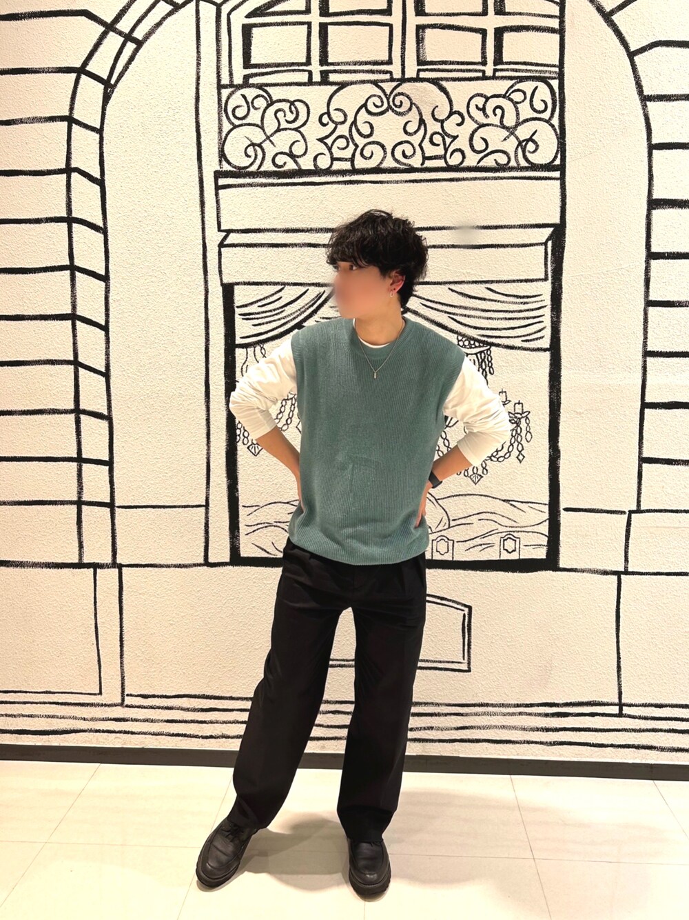 グリーン系のベスト、ブラック系のスラックスを着用したメンズの春コーディネートの1枚目の写真