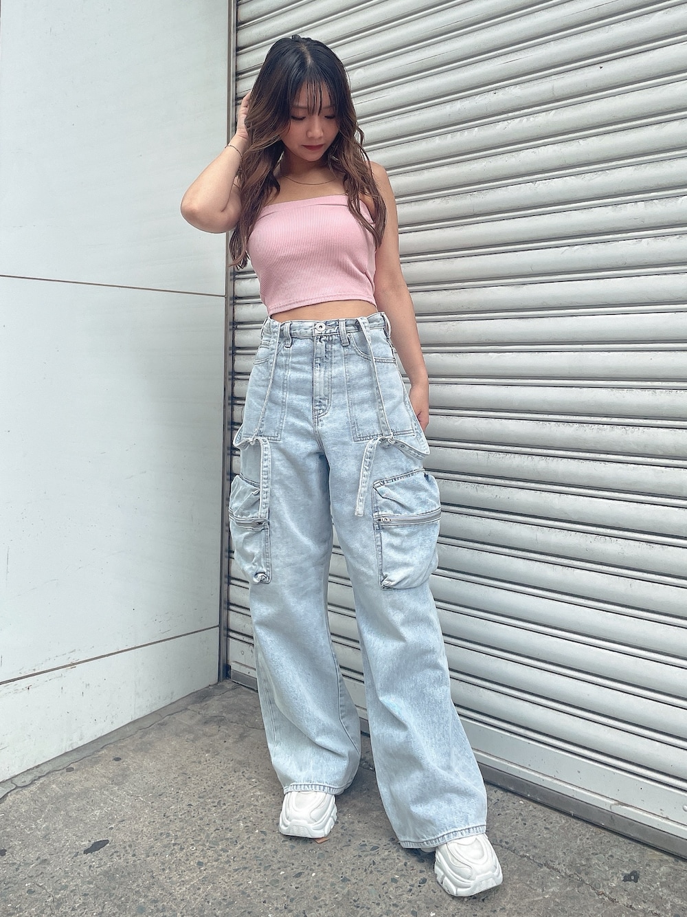 ピンク系のキャミソール、ブルー系のデニムパンツ、ホワイト系のスニーカーを着用したレディースの夏コーディネートの1枚目の写真