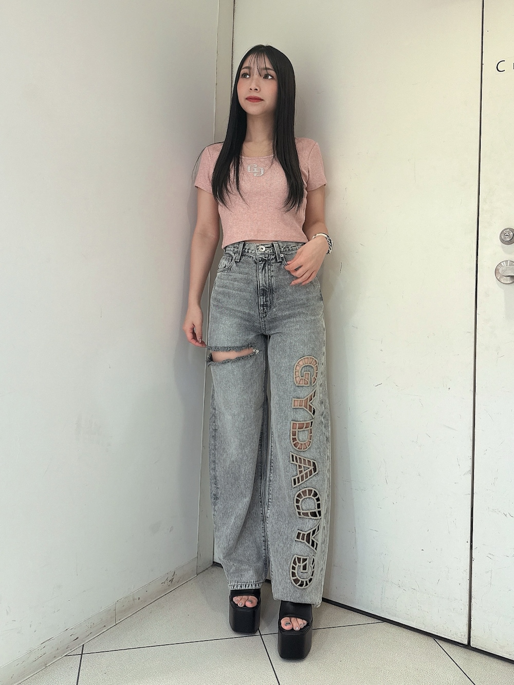 ブルー系のデニムパンツ、ピンク系のTシャツ/カットソー、ブラック系のサンダルを着用したレディースの春コーディネートの1枚目の写真