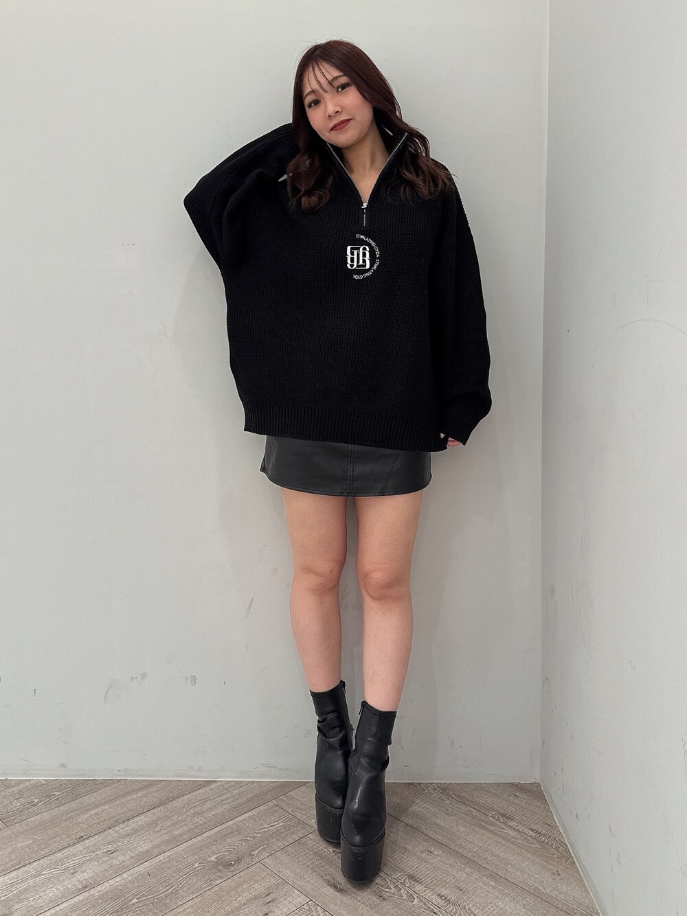 ブラック系のスカート、ブラック系のニット/セーター、ブラック系のブーツを着用したレディースの冬コーディネートの1枚目の写真