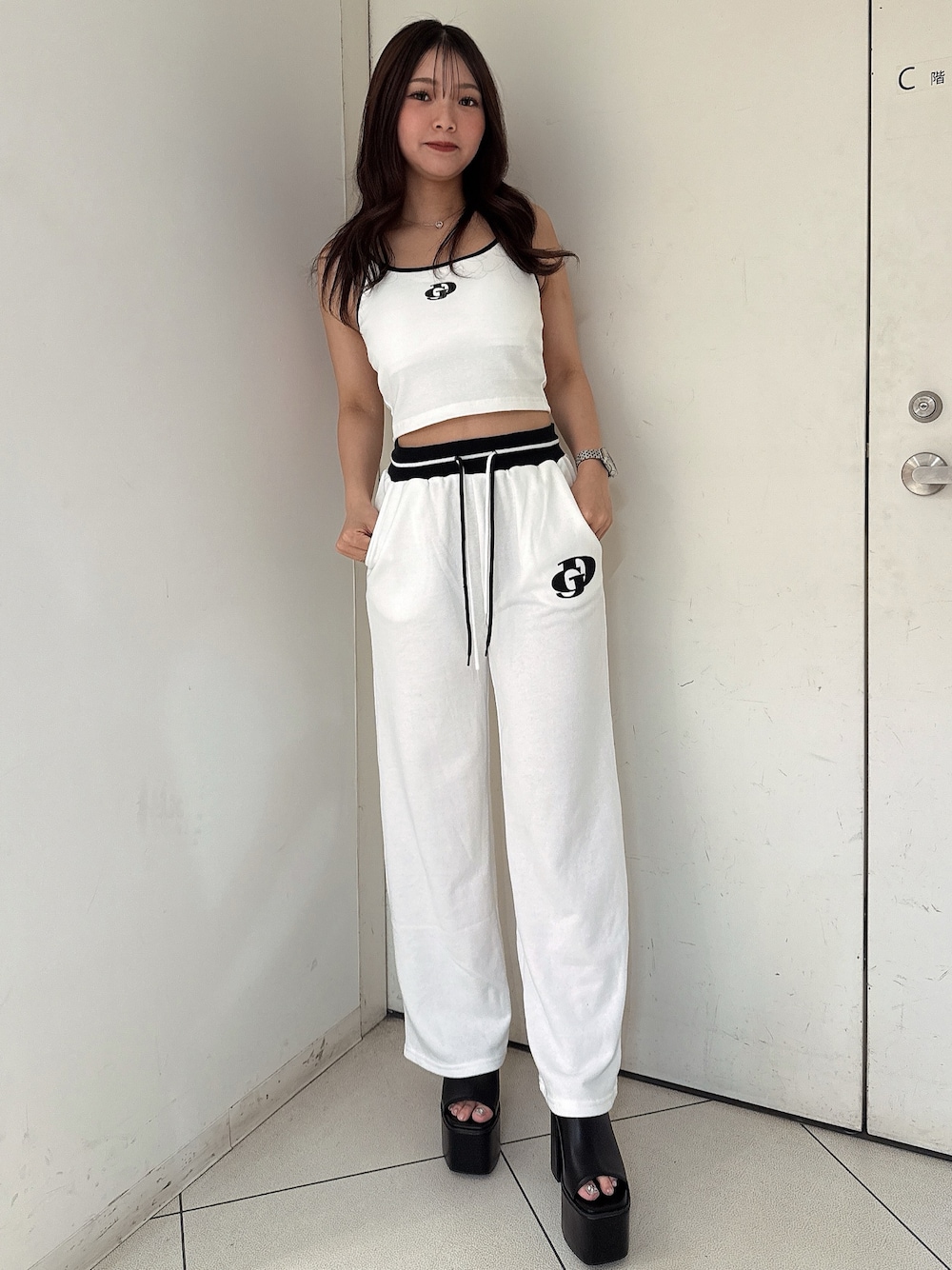 ブラック系のサンダル、ホワイト系のスウェットパンツ、ホワイト系のキャミソールを着用したレディースの夏コーディネートの1枚目の写真