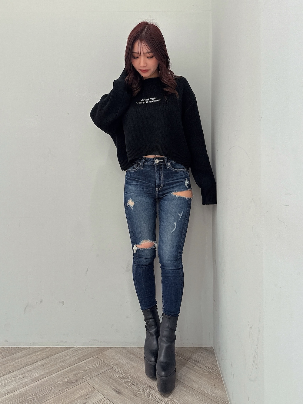 ブラック系のニット/セーター、ブルー系のデニムパンツ、ブラック系のブーツを着用したレディースの秋コーディネートの1枚目の写真