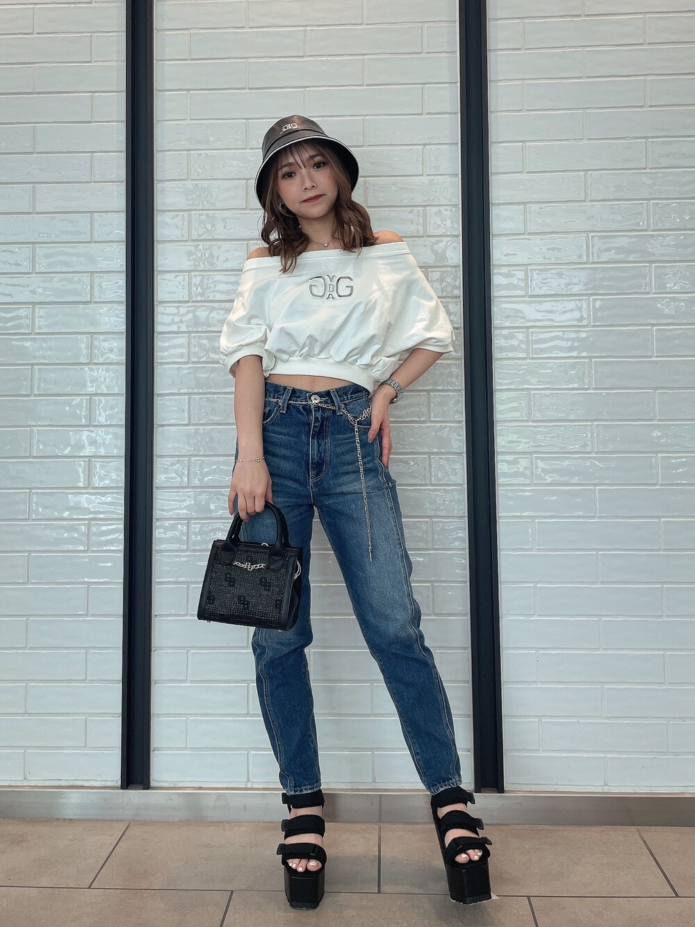 ブルー系のデニムパンツ、ブラック系のハンドバッグ、ブラック系のサンダルを着用したレディースの春コーディネートの1枚目の写真