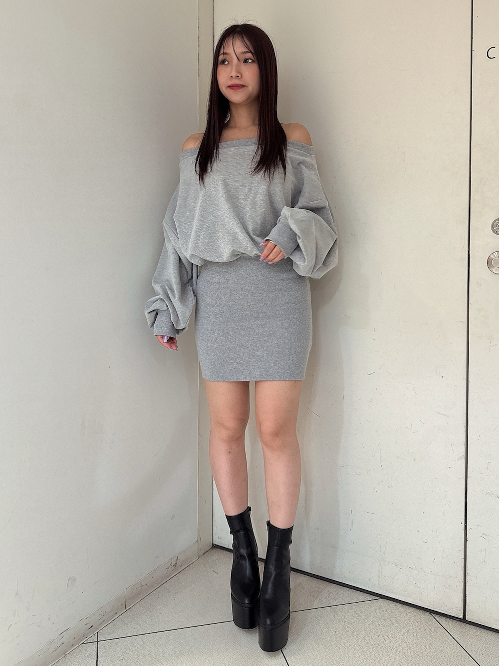 グレー系のワンピース、ブラック系のブーツを着用したレディースの秋コーディネートの1枚目の写真