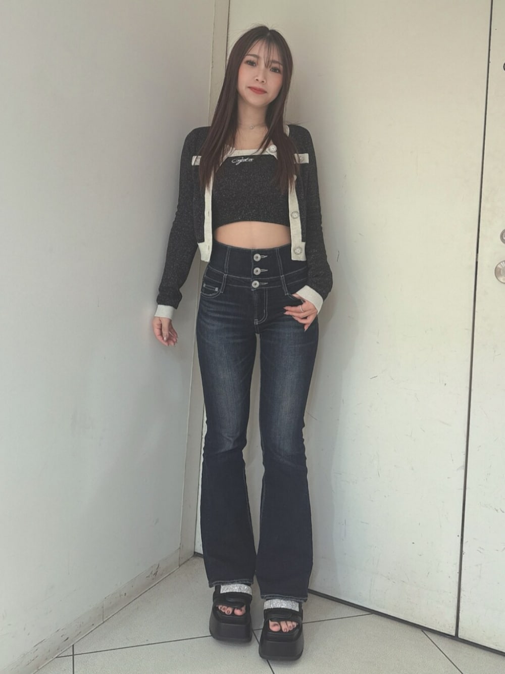 ブルー系のデニムパンツ、ブラック系のサンダル、ブラック系のニット/セーターを着用したレディースの春コーディネートの1枚目の写真