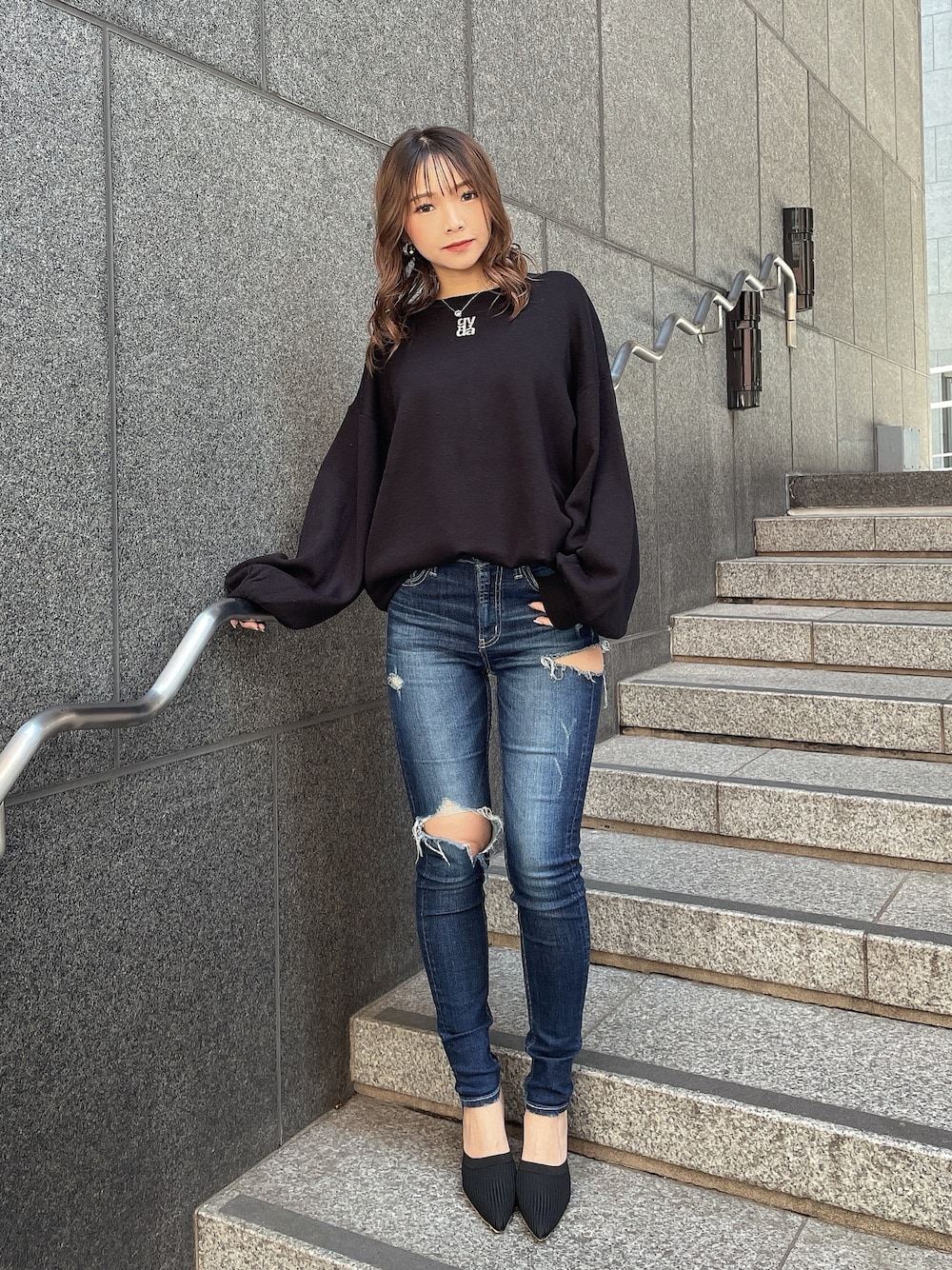 ブラック系のニット/セーター、ブルー系のデニムパンツ、ブラック系のパンプスを着用したレディースの冬コーディネートの1枚目の写真