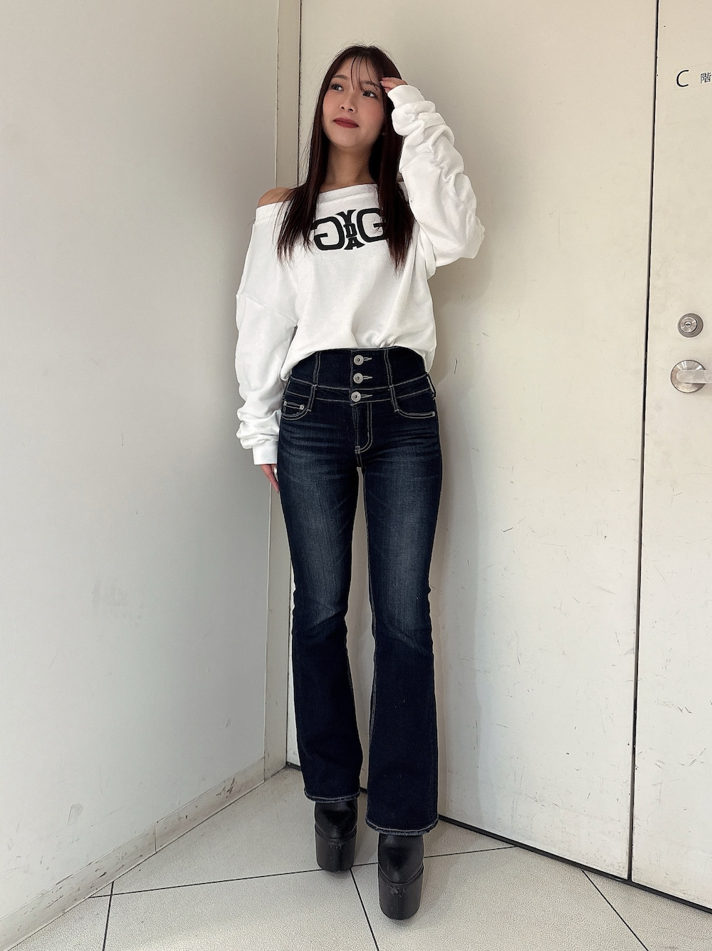 ブルー系のデニムパンツ、ブラック系のブーツ、ホワイト系のスウェットを着用したレディースの秋コーディネートの1枚目の写真