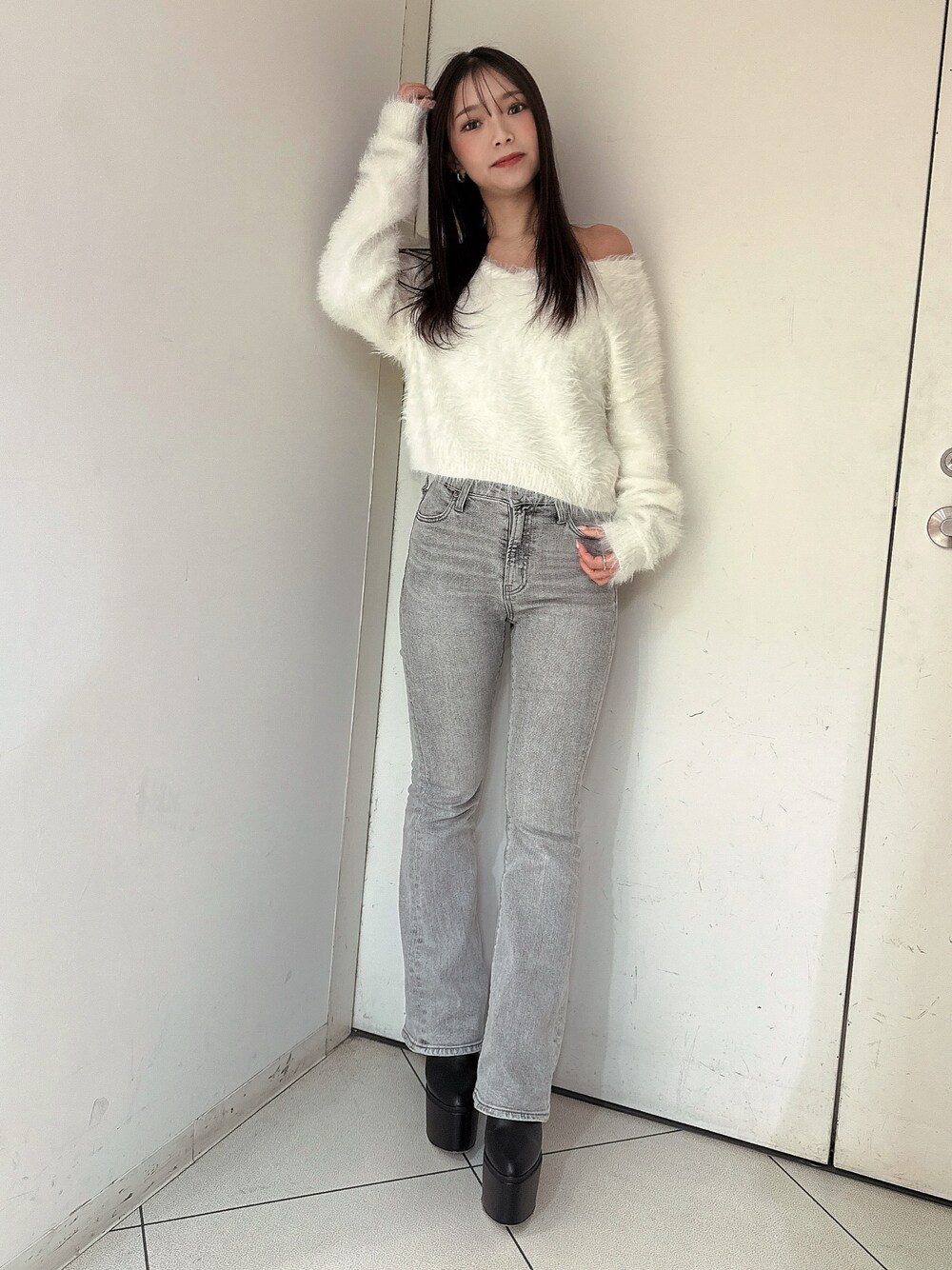 ホワイト系のニット/セーター、グレー系のデニムパンツ、ブラック系のブーツを着用したレディースの冬コーディネートの1枚目の写真